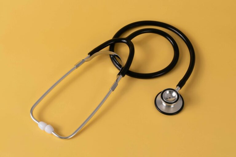 Close-up of a stethoscope on a yellow background, symbolizing healthcare.