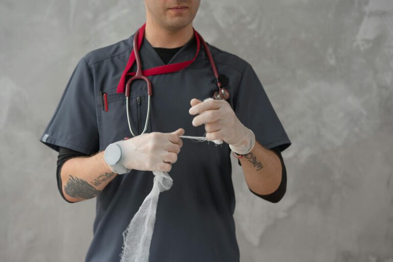 Tattooed medical professional handling gauze with precision and care in a medical setting.